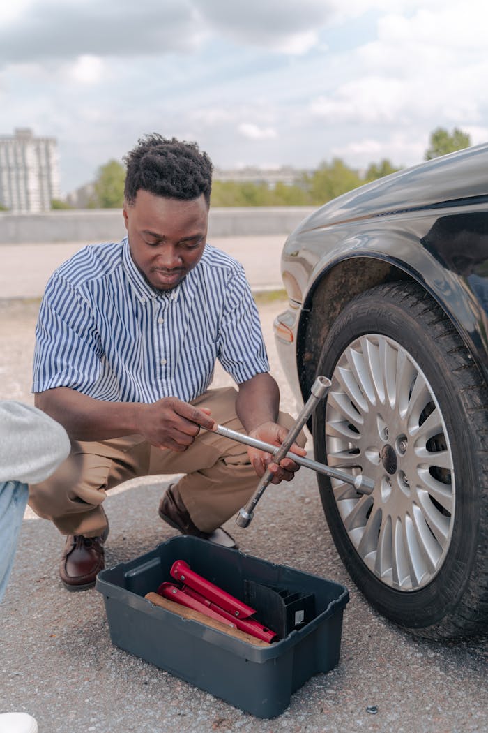 An adult man changing a car tire outdoors using a wrench, showcasing teamwork and learning.